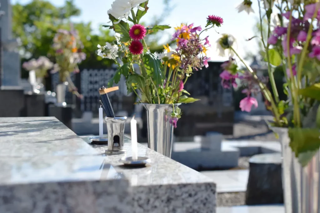 Vases de fleurs et bougies posés sur une pierre tombale en granit.